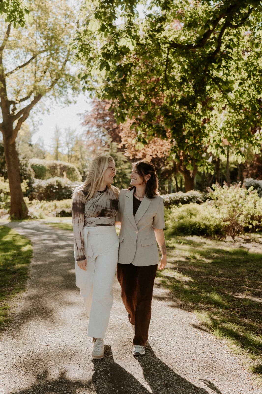 Janine en Claudia samen wandelend door een zonnige laan