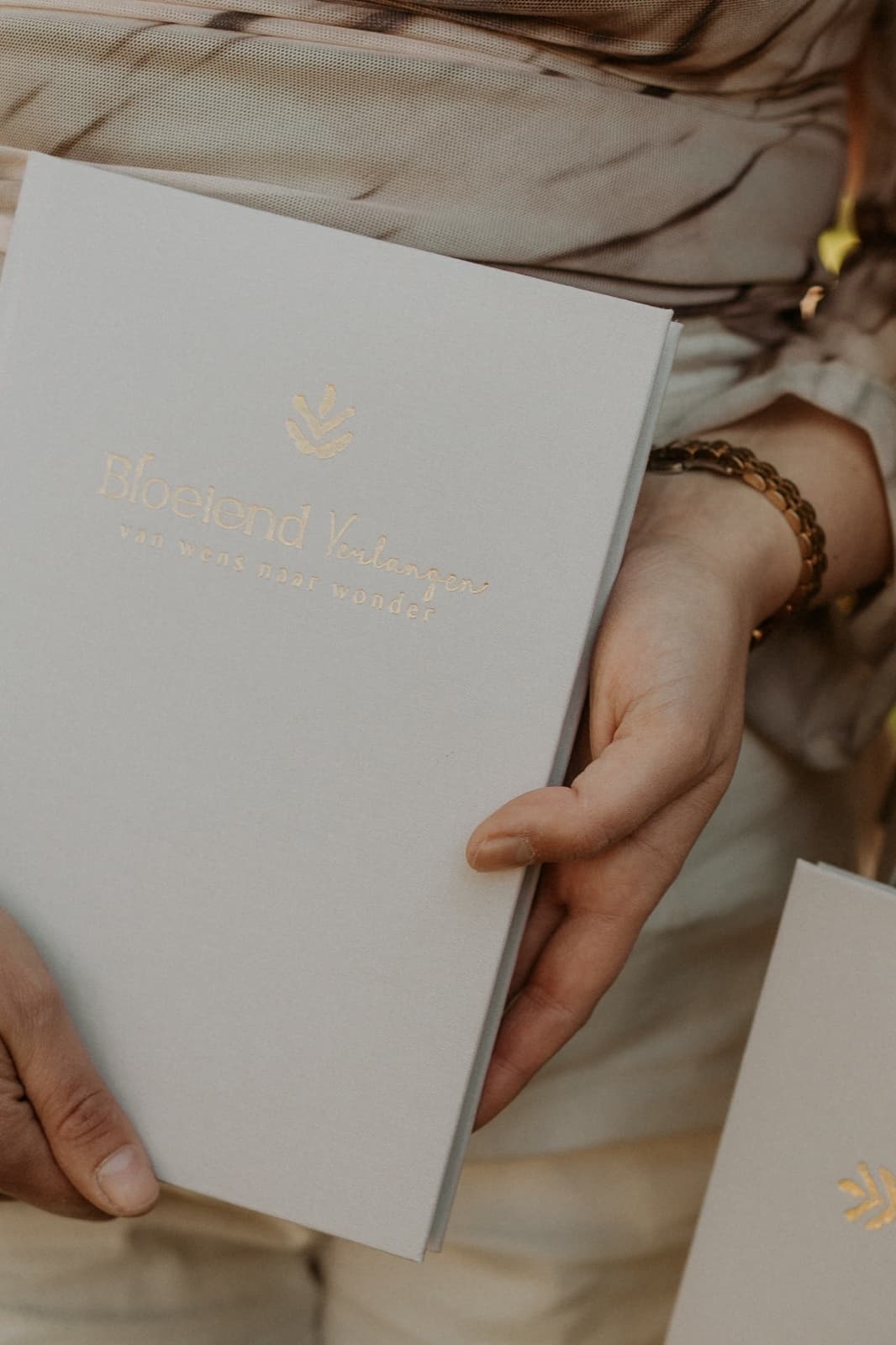 Handen die de cover van het dagboek vasthouden, gouden tagline zichtbaar